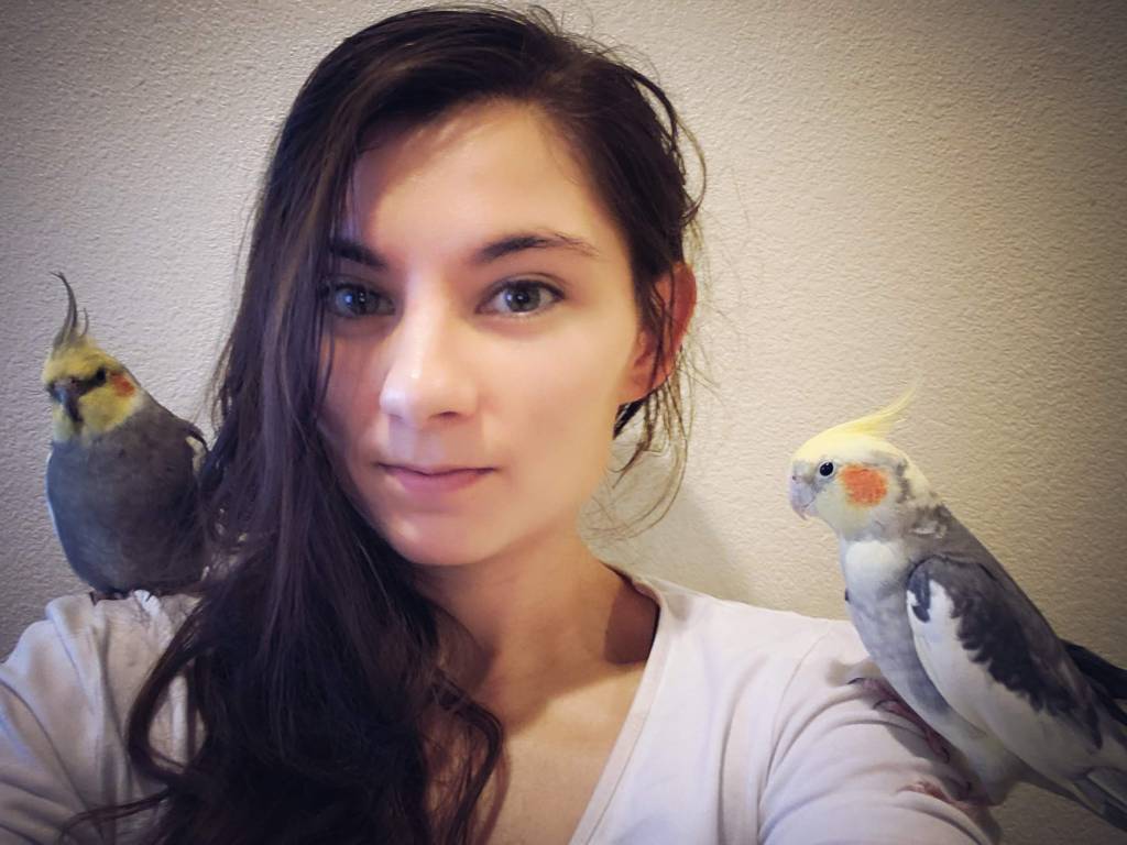 Portrait of Jessica with her two cockatiels, Chirp and Pepper.